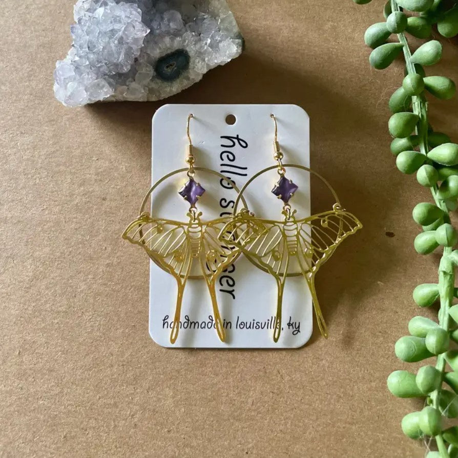 Gold dangle earrings in the shapes of luna moths with purple stones