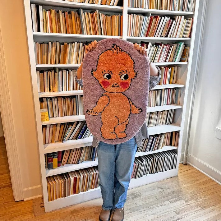 Small lavender rug with the image of a naked smiling kewpie doll on it