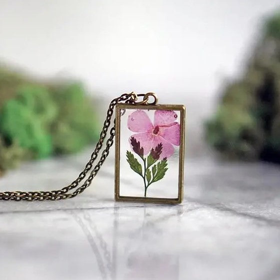 Necklace with a rectangular pendant that showcases a gladiolus flower in resin