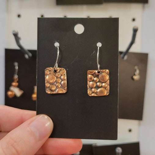 Hand holding copper rectangle earrings