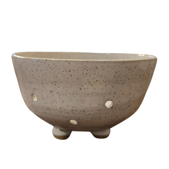 A white speckled pottery bowl with several circular holes along the bottom.