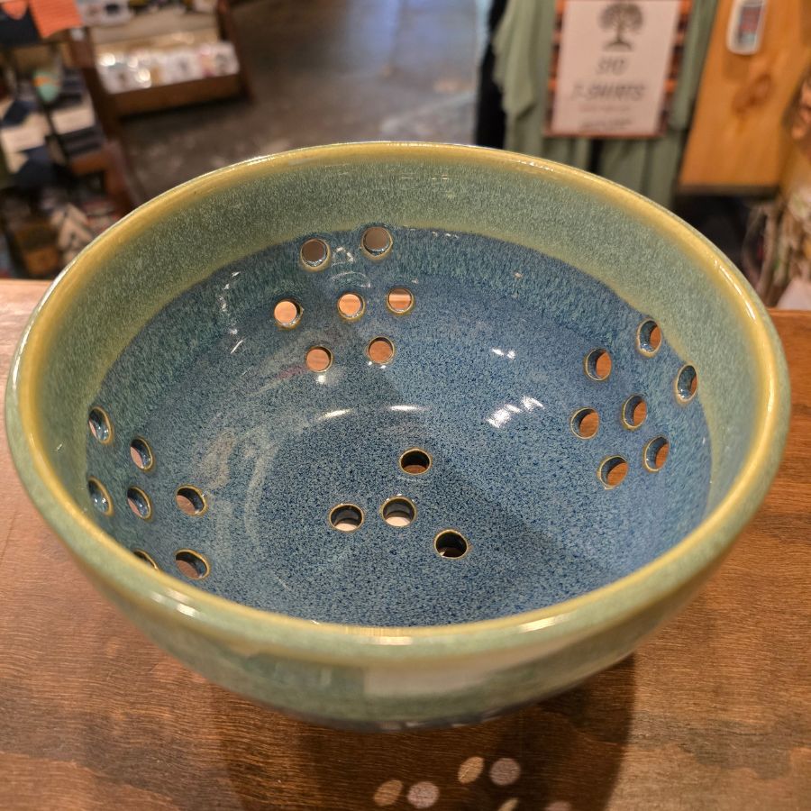A blue and green speckled ceramic bowl with clusters of holes on the bottoms and sides