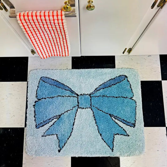A small light blue rectangular shag rug with a blue bow design.