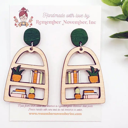 Wooden cutout earrings shaped like bookshelves with potted plants on them