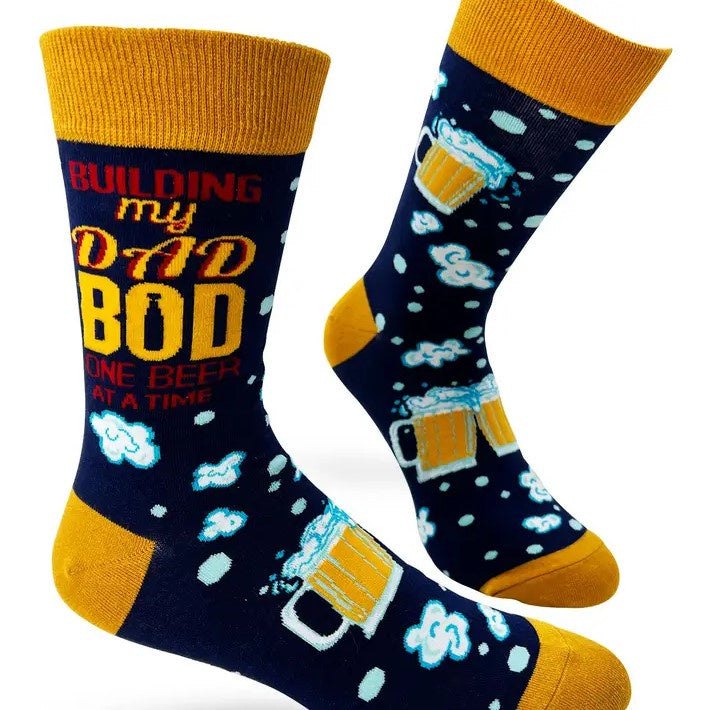 Dark blue socks with bright yellow accents, decorated with mugs of beer and suds and with the words "Building My Dad Bod One Beer at a Time" at the top.