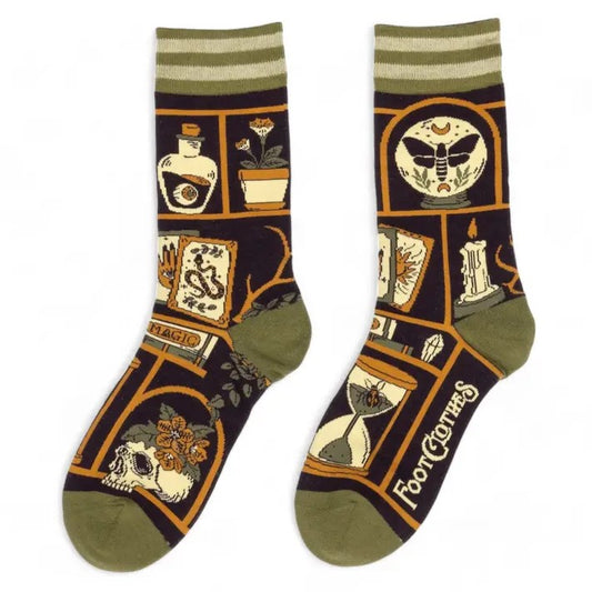 Socks in muted green, yellow and purple featuring images of candles, skulls, tarot cards and various spooky items