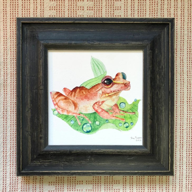 Watercolor art print of an orange Coqui frog on a green leaf