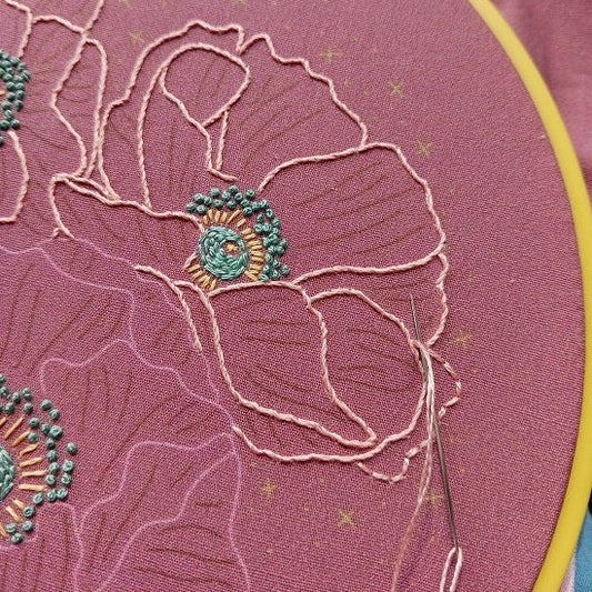 Embroidery hoop with a poppy flower on pink fabric