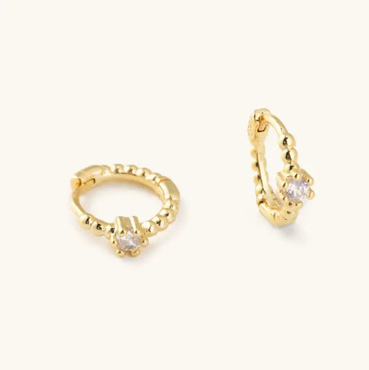 Small gold hoop earrings with a white crystal stone