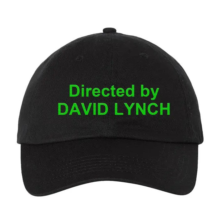 Black ball cap with bright green stitching that reads "Directed by David Lynch"