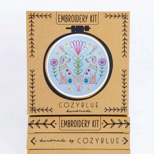 Embroidery hoop featuring two orange dogs surrounded by colorful flowers and plants