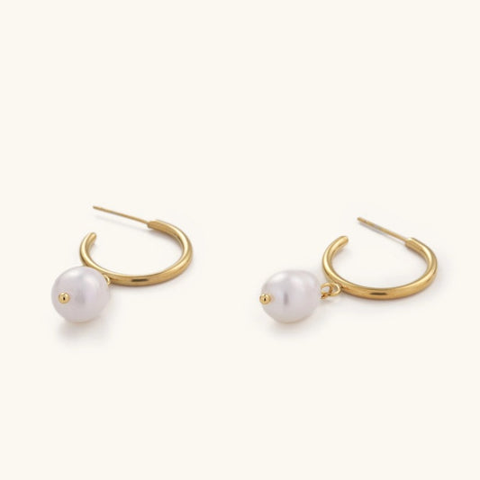 Delicate gold hoop earrings with a small dangling pearl bead