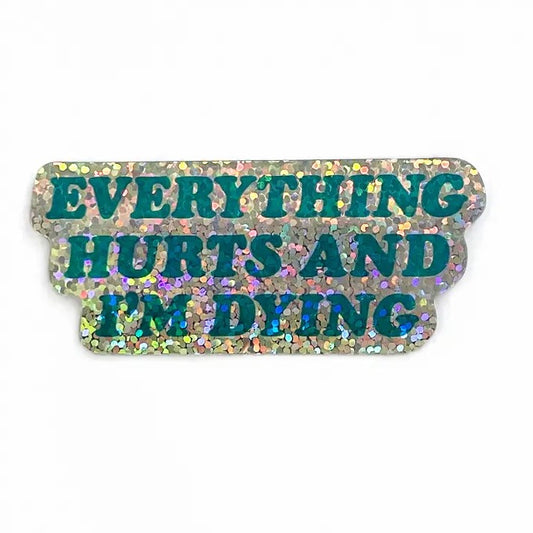 Silver glittery sticker that reads "everything hurts and I'm dying" in blue text