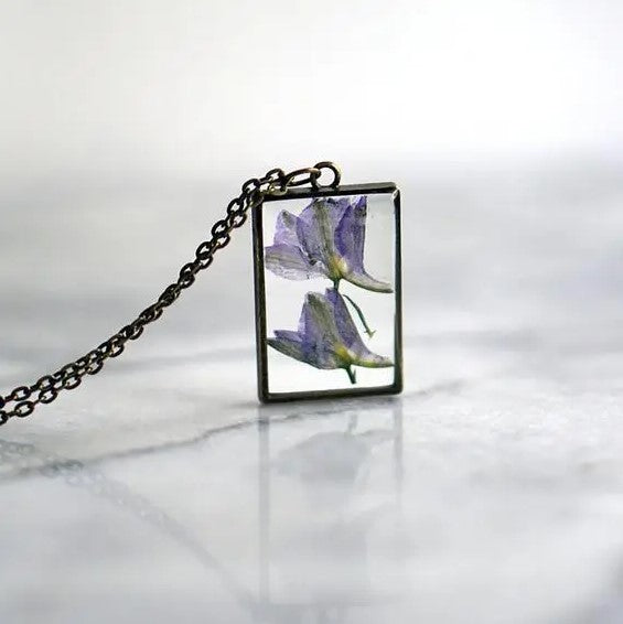Necklace with a rectangular pendant that showcases an iris flower in resin
