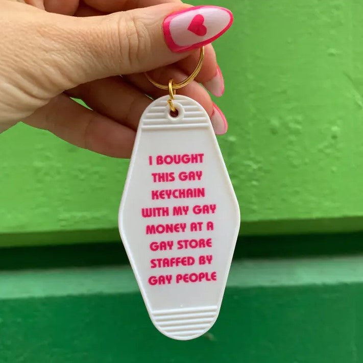 White keychain with hot pink writing that says "I bought this gay keychain with my gay money at a gay store staffed by gay people"