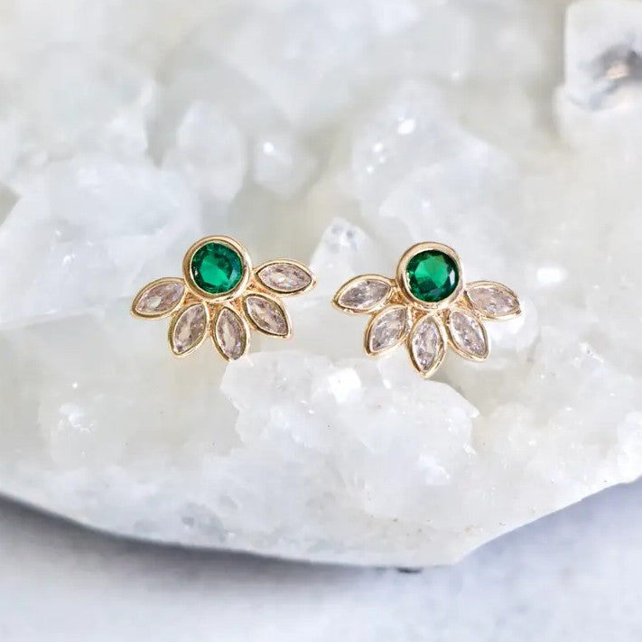 Gold stud earrings with green gemstones surrounded by white crystals in the shape of a flower