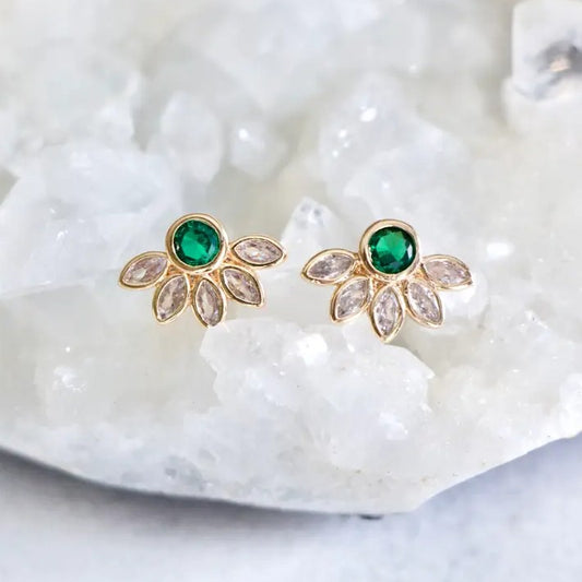 Gold stud earrings with green gemstones surrounded by white crystals in the shape of a flower