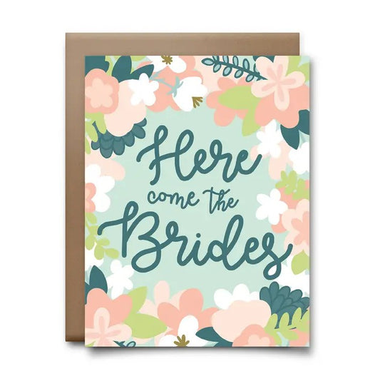 Greeting card with a pastel floral pattern and loopy cursive fond that reads "Here come the Brides"