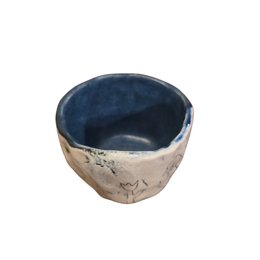 A handmade ceramic cup with a navy blue interior