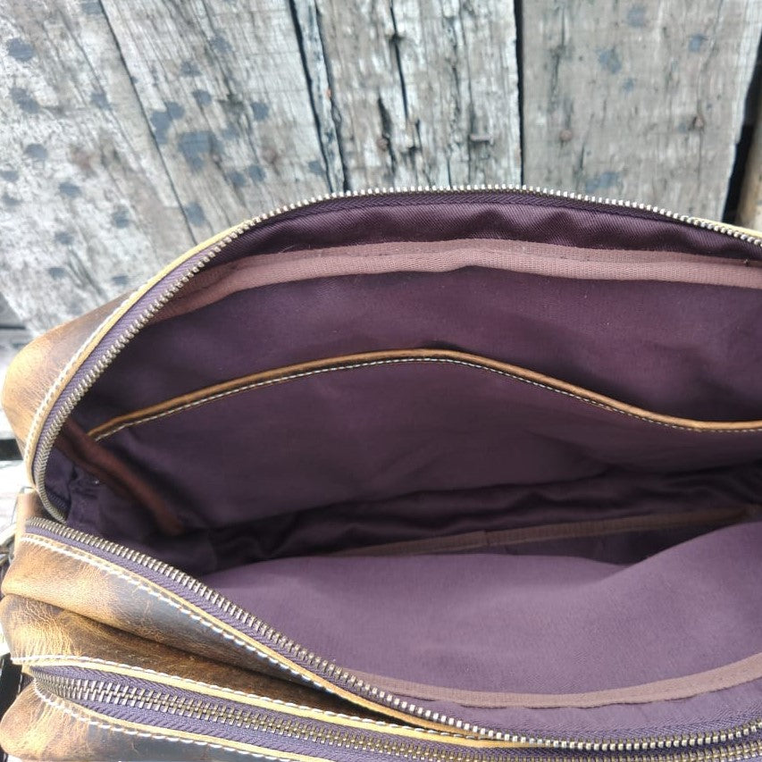 inside of leather bag featuring purple lining and a large pocket