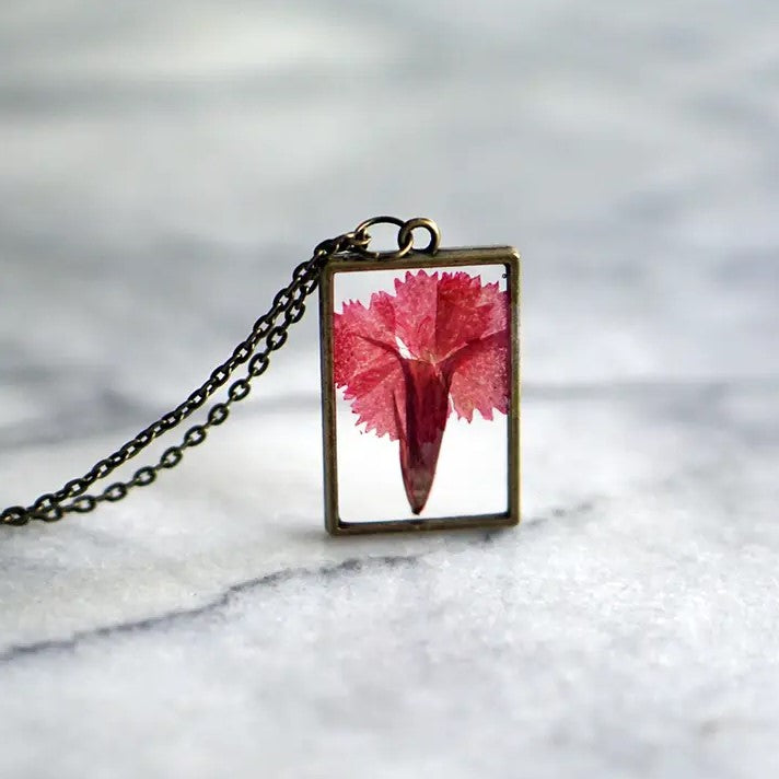 Necklace with a rectangular pendant that showcases a carnation flower in resin