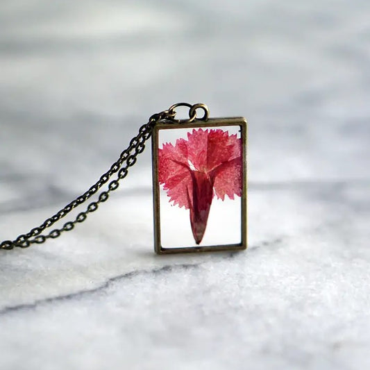 Necklace with a rectangular pendant that showcases a carnation flower in resin