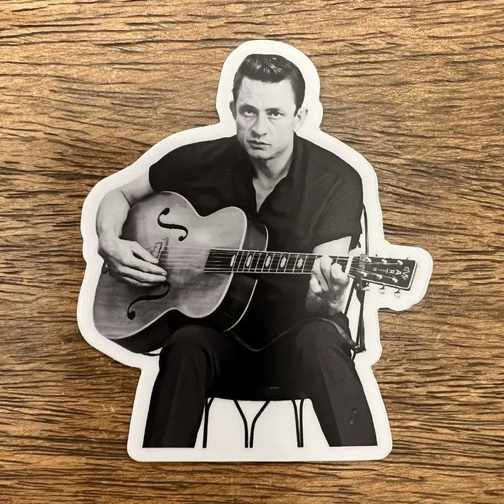 A die-cut sticker featuring a black and white photo of Johnny Cash playing the guitar