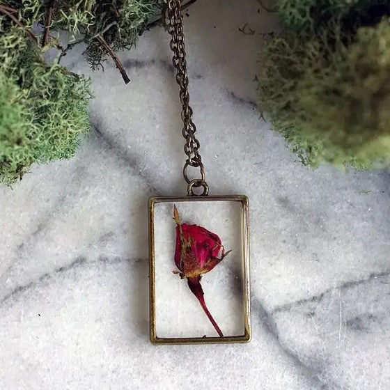 Necklace with a rectangular pendant that showcases a rose flower in resin