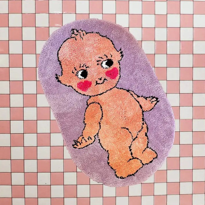 Small lavender rug with the image of a naked smiling kewpie doll on it
