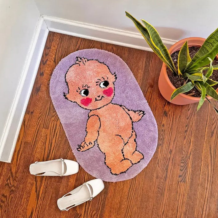 Small lavender rug with the image of a naked smiling kewpie doll on it