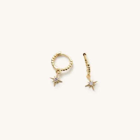 Small gold huggie earrings with a star shaped hanging charm