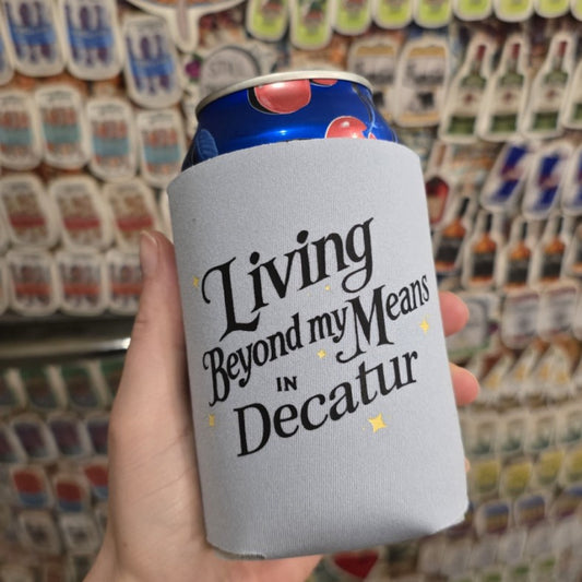 Gray koozie that reads "Living beyond my means in Decatur"