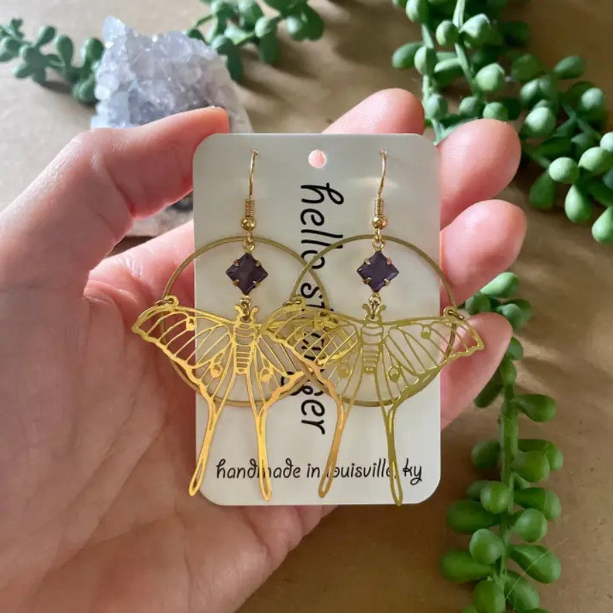 Gold dangle earrings in the shapes of luna moths with purple stones