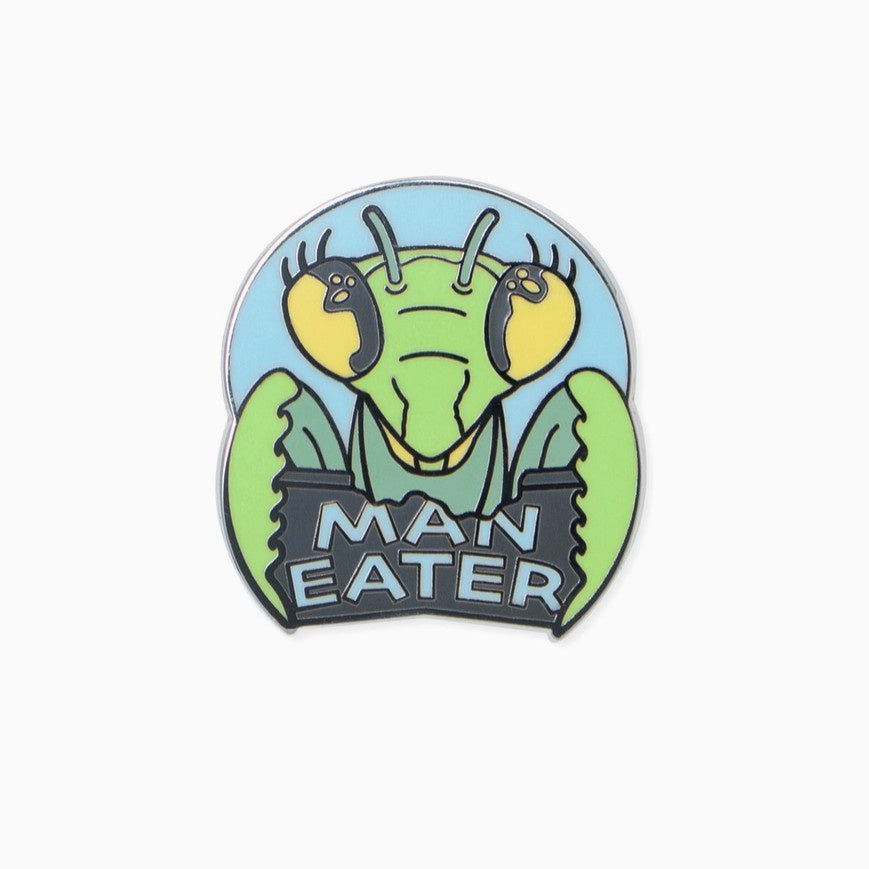Enamel pin shaped like a praying mantis head with the words "Man Eater" underneath