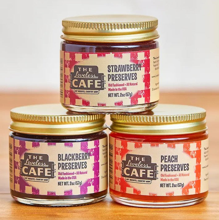 Three two ounce jars of fruit preserves on a wooden table