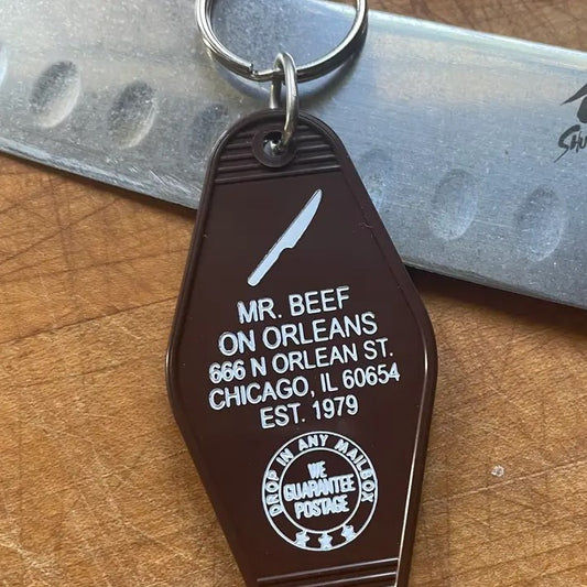 Dark brown keychain with a small image of a knife and the words "Mr. Beef on Orleans 666 N Orlean St. Chicago, IL 60653 Est 1979."