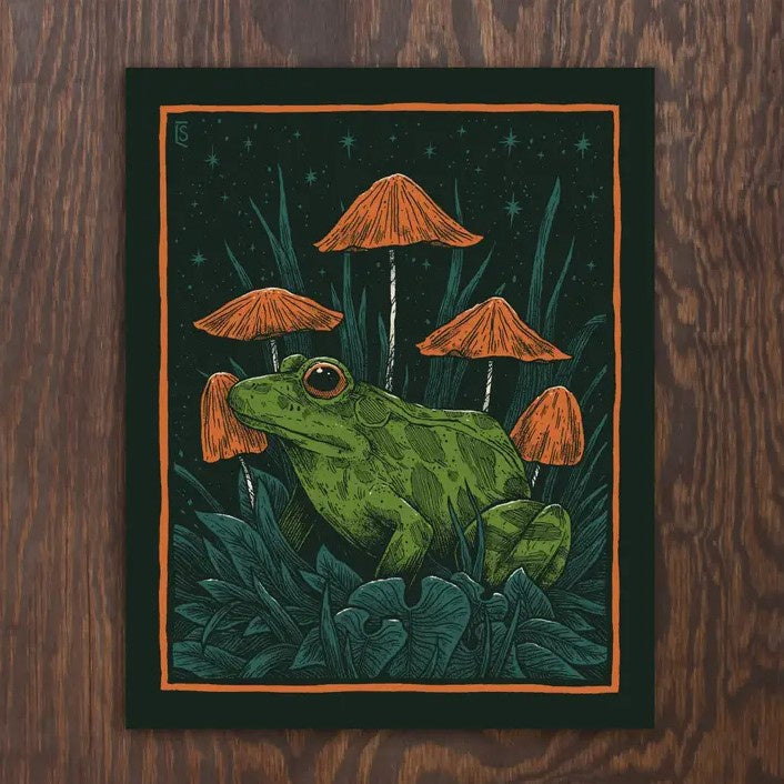 A dark blue 8x10 print depicting a frog drawn in a sketchy style nestled in leaves and orange mushrooms in front of the night sky.