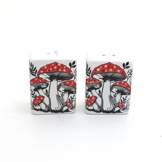 White ceramic salt and pepper shakers with black and red mushrooms on them