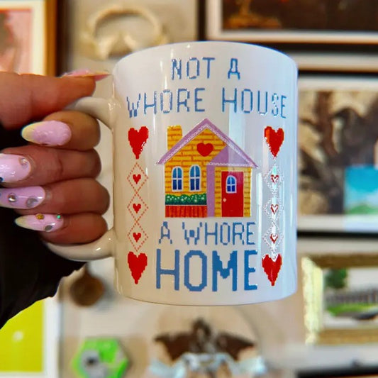 White mug with a colorful illustration of a house and the words "Not a whore house, a whore home"