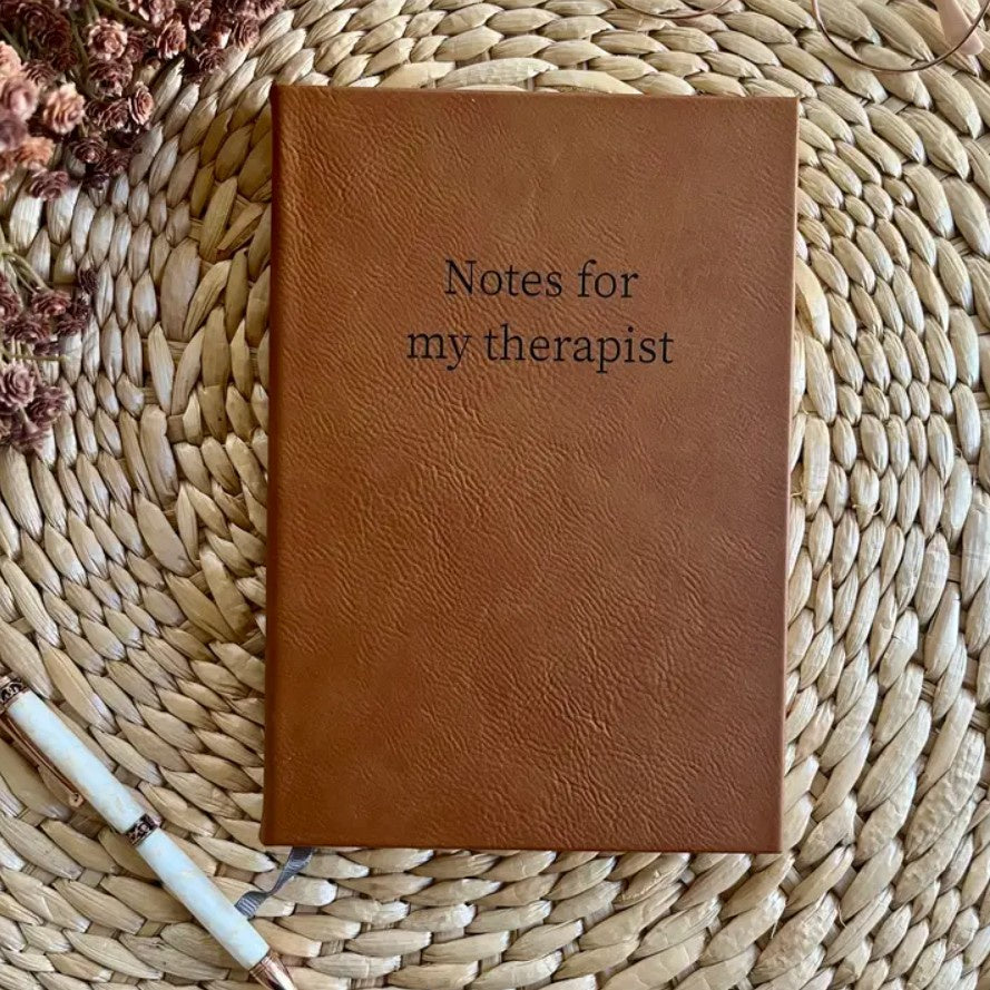 Brown leather journal with the words "Notes for my therapist" in black font on the cover