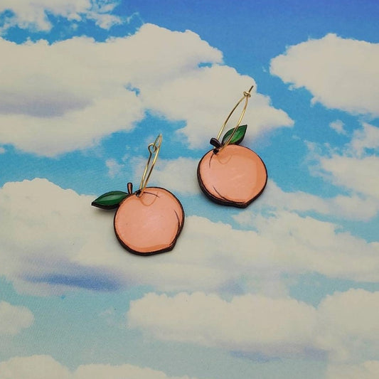 Gold hoop earrings with dangling peaches carved from wood and painted