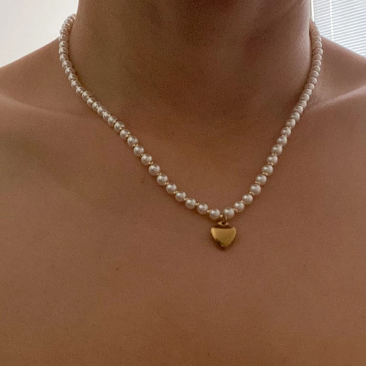 Choker length pearl bead necklace with a heart shaped gold charm as a pendant