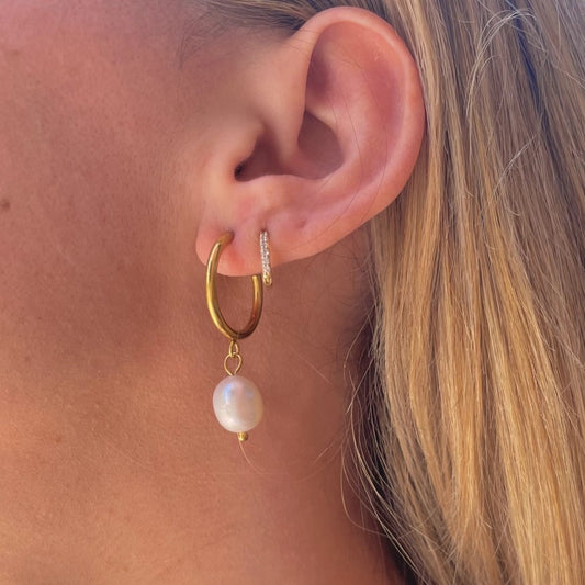 Delicate gold hoop earrings with a small dangling pearl bead