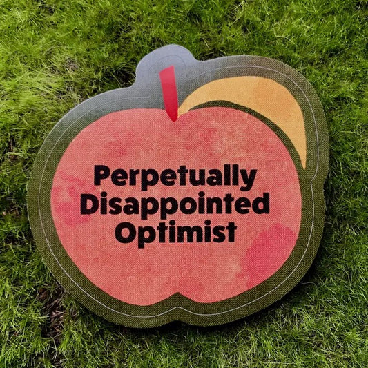 Sticker featuring a simplified cartoon peach on a dark background, with black text that reads "perpetually disappointed optimist"