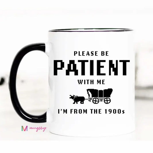White mug with black pixelated text reading "Please be patient with me, I'm from the 1900s" and a pixel image of an ox-drawn cart