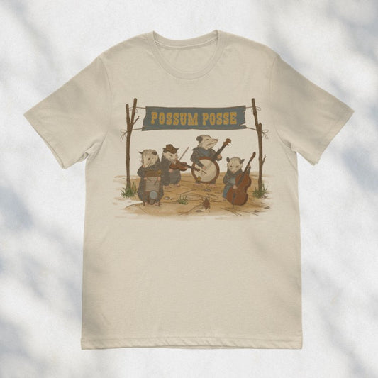 Beige tee shirt with an image of four possums in the desert playing in a country band, under a banner that says "Possum Posse"