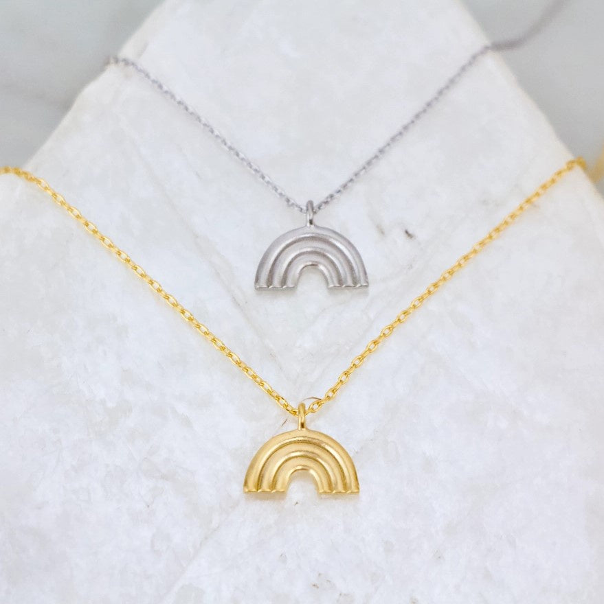 A necklace featured in both gold plated and silver plated options with a small rainbow shaped pendant