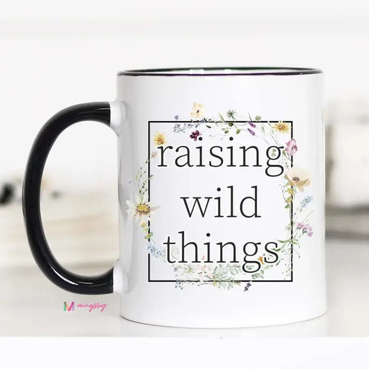 White mug with the words "raising wild things" surrounded by wildflowers