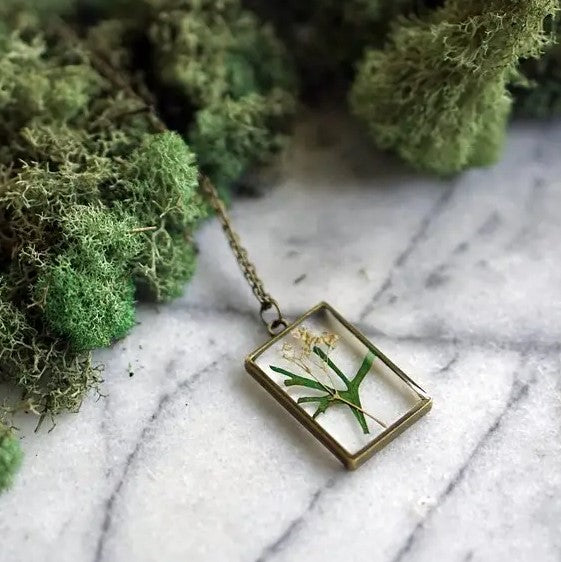 Necklace with a rectangular pendant that showcases a lily of the valley flower in resin