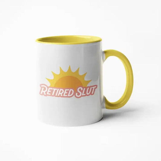 White mug with a yellow interior and handle and the words "Retired Slut" under an image of a setting sun